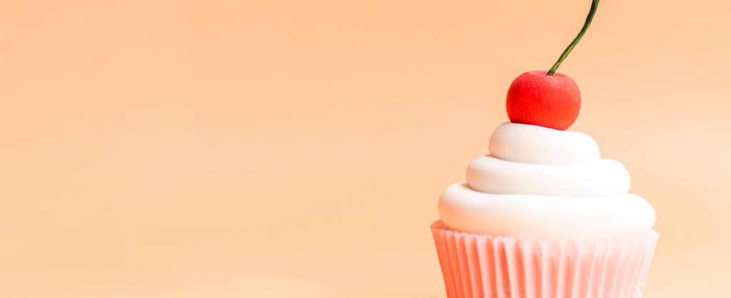 Photograph of a cupcake with a cherry on top.